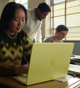 Eine Schülerin verwendet ein MacBook Neo in der Farbe Zitrus, das nicht am Strom angeschlossen ist, in einem Klassenzimmer